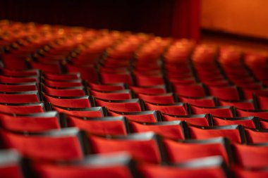 Sandalyeler arasında simetrik çerçeveli birkaç kırmızı sinema koltuğu..