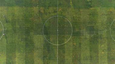 Yukarıdan görülen futbol sahası (doruk), yeşil rengi, işaretlerini ve çimlerin üzerindeki bazı yamaları vurgulayan drone tarafından görülür..