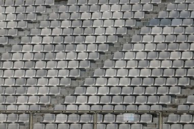 Grili bir futbol stadyumunun tribünleri, hiç insan olmadan, ve farklı gölgelerde çitler..
