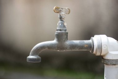 Fıskiyeye odaklanmış su musluğu ve geri kalanı bulanıklaştı. Resmin nötr renkleri var ve delikten hiç su çıkmıyor..