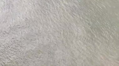Su hareketinin en uç noktasından drone görüntüsü, biraz bulutlu. Görüntüde hafif dalgaları olan suya odaklanan hafif bir kamera hareketi var..