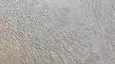 Su hareketinin en uç noktasından drone görüntüsü, biraz bulutlu. Görüntüde hafif dalgaları olan suya odaklanan hafif bir kamera hareketi var..