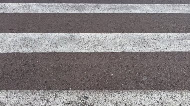 Yaya geçişleri için şehirlerde kullanılan dikdörtgen beyaz paralel geçitler. Görüntü asfaltın dokusunu gösteriyor ama insan yok..