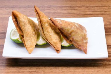 Lezzetli samosa tabağı ve ahşap arka planda samosa.