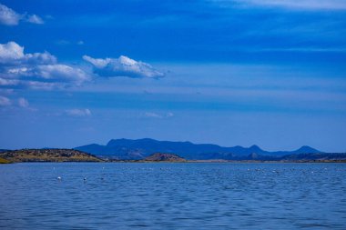 Dağları ve mavi gökyüzü olan güzel bir göl manzarası.