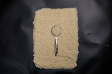 Bir kaşık ve siyah arka planda kaşıkla beyaz bir tabak.