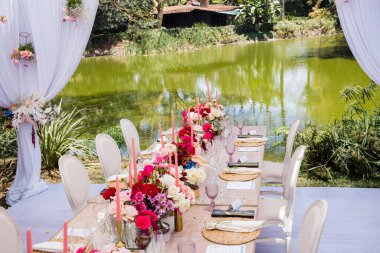 Çiçekli, mumlu ve gözlüklü düğün masası.