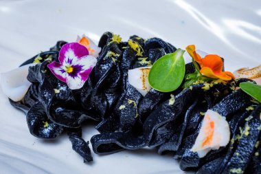 Beyaz tabakta siyah havyarlı makarna..