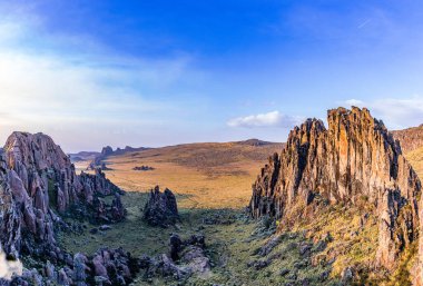 Dağlarla ve mavi gökyüzüyle manzara. Güneş kayalara yansıyor..