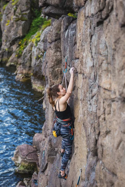 女の子は水の上に岩を登ると 女性は極端なスポーツに従事している 自然の地形 強さと持久力の訓練にロッククライミング — ストック写真