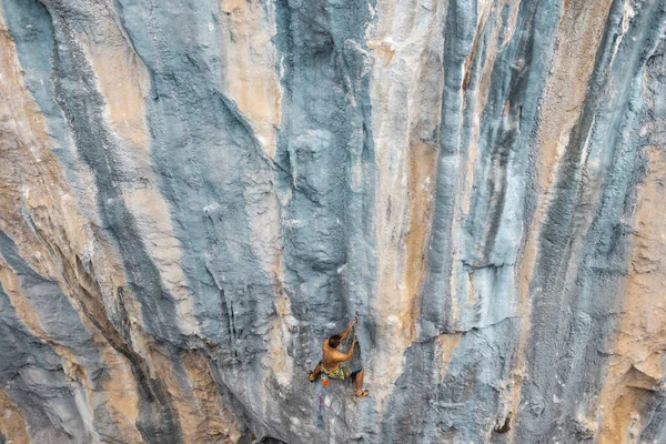 Extreme sport, a strong man climbs a rock, a rock climber climbs a difficult route.