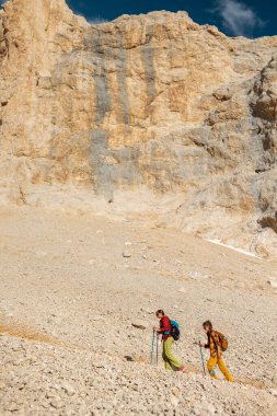 Dağlarda sırt çantalı iki turist. Turistler kayalık dağlarda seyahat ederler. Dağ yürüyüşünde aktif dinlenme. Dağlarda macera. Grup yürüyüşü