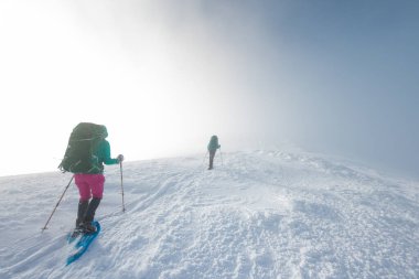 two girls walk along a mountain path in snowshoes. walking in the snow. hiking in the mountains in winter.