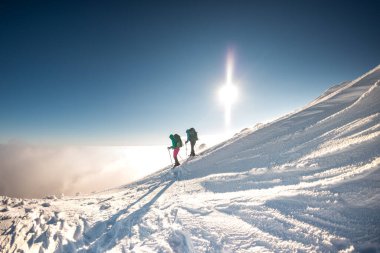 Karla kaplı bir dağa tırmanmak, kış yürüyüşünde iki kadın, dağcılar kışın dağın zirvesine tırmanmak.