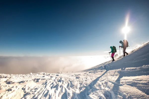 雪に覆われた山を登る冬のトレッキングをする2人の女性登山家は冬に山の頂上に登る — ストック写真
