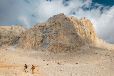 Dağlarda sırt çantalı iki turist. Turistler kayalık dağlarda seyahat ederler. Dağ yürüyüşünde aktif dinlenme. Dağlarda macera. Grup yürüyüşü