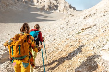 Dağlarda sırt çantalı iki turist. Turistler kayalık dağlarda seyahat ederler. Dağ yürüyüşünde aktif dinlenme. Dağlarda macera. Grup yürüyüşü