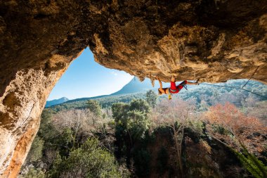 Tepeye tırmanmış genç bir kaya tırmanıcısı. Dağcı kayaya tırmanır. Kız spor tırmanışı ile meşgul. Doğada spor.