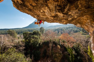 Tepeye tırmanmış genç bir kaya tırmanıcısı. Dağcı kayaya tırmanır. Kız spor tırmanışı ile meşgul. Doğada spor.
