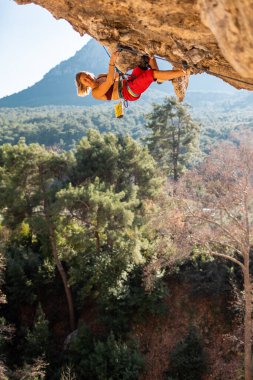 Tepeye tırmanmış genç bir kaya tırmanıcısı. Dağcı kayaya tırmanır. Kız spor tırmanışı ile meşgul. Doğada spor.