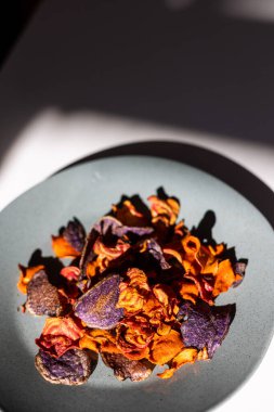 Close-up of orange and red carrot and beet chips on a plate. Organic vegetable chips.