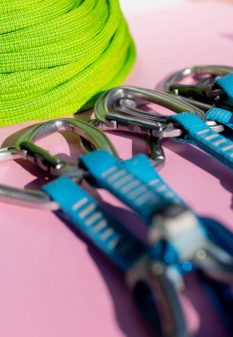 green rope and climbing and mountaineering equipment lies on a colored background. background image of rope and equipment for active sports. sports equipment