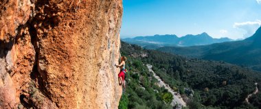 The girl climbs the rock. Climber trains on natural terrain. Extreme sport. Lessons on the street. A woman overcomes a difficult climbing route in Turkey. sports and adventure.