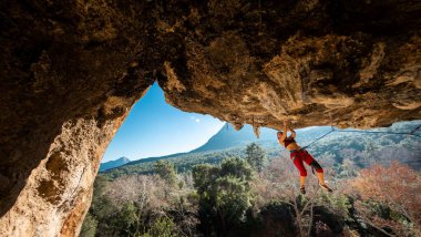 Tepeye tırmanmış genç bir kaya tırmanıcısı. Dağcı kayaya tırmanır. Kız spor tırmanışı ile meşgul. Doğada spor.