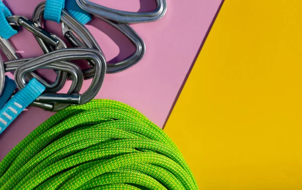 green rope and climbing and mountaineering equipment lies on a colored background. background image of rope and equipment for active sports. sports equipment