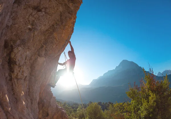 アスレチックマンはロープでオーバーハングした岩を登り クライミングをリードします 山を背景にロッククライマーのシルエット アウトドアスポーツやレクリエーション — ストック写真