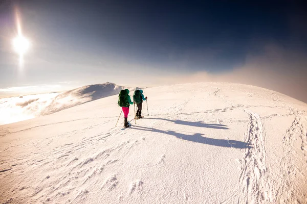 雪の嵐の中リュックとスノーシューズを着た2人の女の子が雪の中を歩く 大きな山での登山 — ストック写真