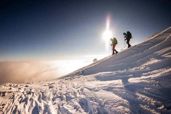 観光客は冬に山の中で一緒に旅行します 2人の女の子雪の山のキャップ スノーシューで山をハイキングし — ストック写真