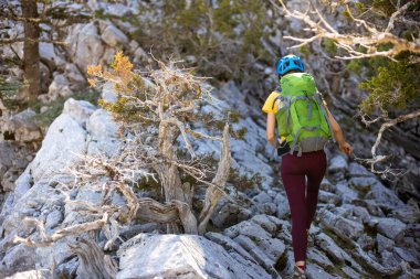Sırt çantası ve dağlarda miğferi olan bir kadın tırmanıcı. macera ve dağcılık konsepti. Dağlarda bir sırt çantasıyla yürüyüş yapmak. Türkiye dağları.