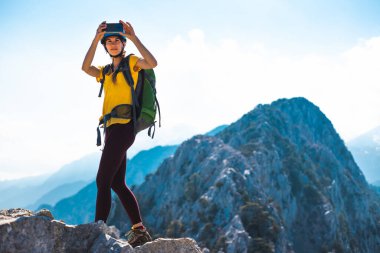 Dağın tepesindeki dağcı fotoğraf çekiyor. Kadın gezgin modern bir akıllı telefondan fotoğraf çeker, güzel dağ manzaralarının güzel resimlerini çeker. dağ tırmanışı ve macera.