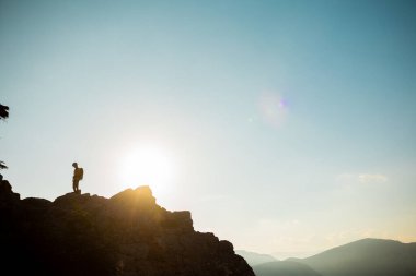 Sırt çantalı bir kızın silueti dağ sıralarında yürüyor. Dağın tepesine tırmanan biri. Spor ve aktif yaşam kavramı. dağlarda dolaşmak.