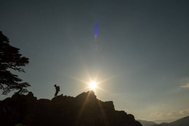 Sırt çantalı bir kızın silueti dağ sıralarında yürüyor. Dağın tepesine tırmanan biri. Spor ve aktif yaşam kavramı. dağlarda dolaşmak.