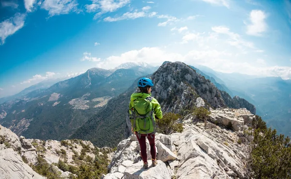 Woman climber with a backpack and a helmet in the mountains. A girl with a backpack walks along a mountain range. adventure and mountaineering concept. hiking with a backpack in the mountains.