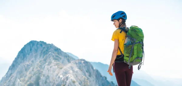 헬멧을 착용하고 등산하는 여자는 여름철에 등산을 경관을 즐긴다 — 스톡 사진
