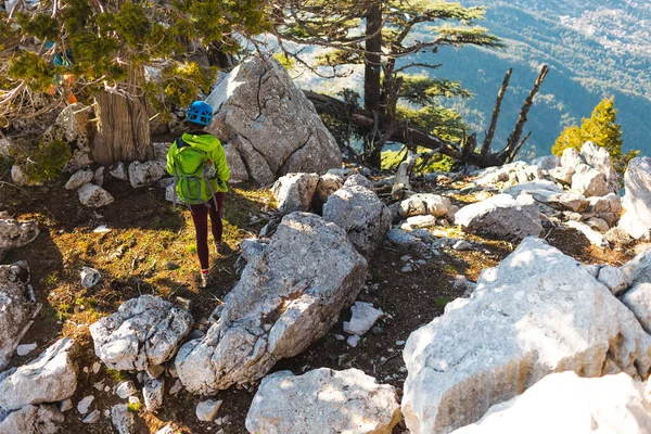 Woman climber with a backpack and a helmet in the mountains. A girl with a backpack walks along a mountain range. adventure and mountaineering concept. hiking with a backpack in the mountains.