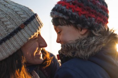 Anne mutlu oğluna bakıyor. Annesinin yanında kışlık giysiler içindeki bir çocuğun portresi..