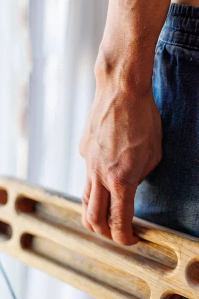 strong male hand of a rock climber holds a board for training finger strength. climbing workout. rock climber\'s hand close-up. strength and endurance. fingerboard and hangboard. extreme sport