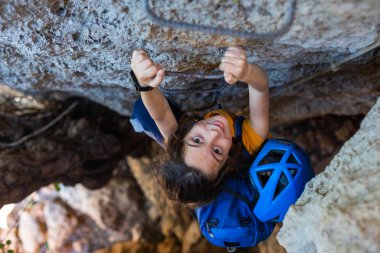 Kasklı ve sırt çantalı bir çocuk dağlarda. Çocuk tatilde. Çocuk taşlara tırmanıyor..
