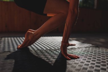 Kız yoga yapıyor. Doğadaki sınıf. Kadınların elleri aşağı iner ve avuçlarıyla halıya dokunur. Eller ve ayaklar yoga minderine yakın çekim. sakinlik ve meditasyon kavramı.