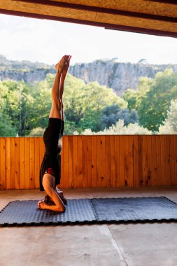 Kız yoga yapıyor. Genç atletik kadın antrenör yoga eğitmeni bireysel antrenman yapıyor. Denge pozisyonu, modern spor salonu, sağlıklı yaşam tarzı konsepti. Doğada spor