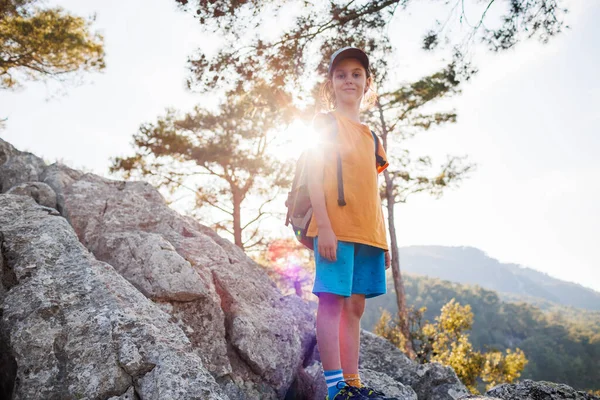 旅行中の子供 バックパックを持った観光客が山道に立って山を眺めます ハイキングや健康的なライフスタイルです 子供たちとの冒険の休日 — ストック写真