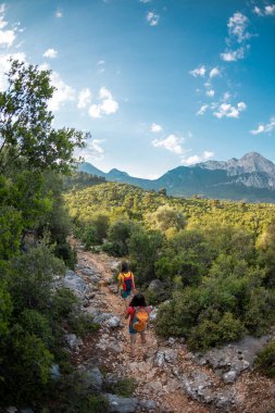 Sırt çantalı iki kız dağ yolunda yürüyorlar, güzel bir dağ ve gökyüzünün zeminine karşı kadınlar, dünyanın güzel yerlerinde bir yolculuk, Türkiye 'ye seyahat