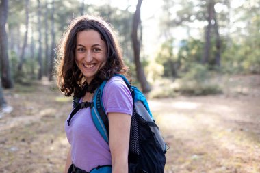 Sırt çantasıyla ormanda yürür, güneşli bir günde dağlarda yürüyüş yapar..