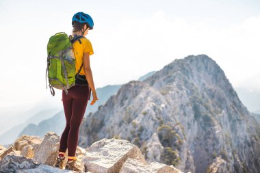 Dağcı dağın tepesinde duruyor. Kasklı ve sırt çantası dağlı bir kız. Macera konsepti ve dağlarda yürüyüş. Türkiye.