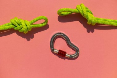 İple çizilmiş karabina renkli bir arka planda yatıyor. Tırmanma ve dağcılık ekipmanları. Güvenilir bağlantı. Güvenlik halatı. Sekiz nod. Güvenilirlik ve güç kavramı. Boşluğu kopyala.