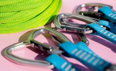 green rope and climbing and mountaineering equipment lies on a colored background. background image of rope and equipment for active sports. sports equipment